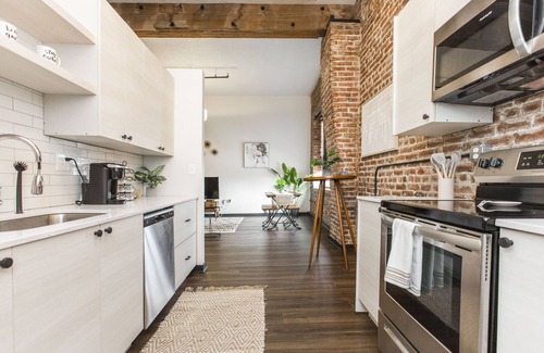 Kansas City Apartment | Exposed brick, wood beams, & chic touches give this loft serious style. Enjoy skyline views from the rooftop, a full kitchen with coffee bar, king bed, on-site gym, & quick access to the free KC streetcar. Walk to shops/dining, and the City Market!