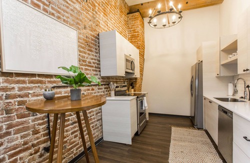 Kansas City Apartment | Exposed brick, wood beams, & chic touches give this loft serious style. Enjoy skyline views from the rooftop, a full kitchen with coffee bar, king bed, on-site gym, & quick access to the free KC streetcar. Walk to shops/dining, and the City Market!