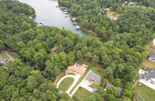 Flowery Branch House | Lakefront 4BR/6BA home with private dock, fire pit, smart TVs in all rooms, sunroom, BBQ grill, and fenced game yard. Includes golf cart, 2 fridges, double oven, and more. 1 mile to Aqualand Marina & Pig Tales Restaurant.