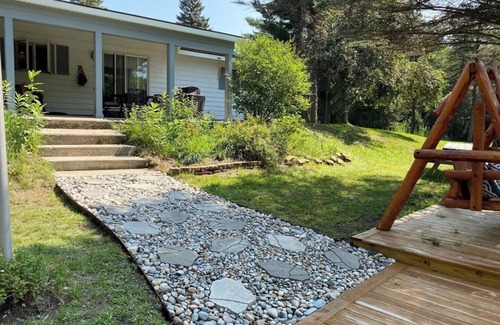 Grayling House | Riverfront Escape in Downtown Relax on the Covered Patio with the Family