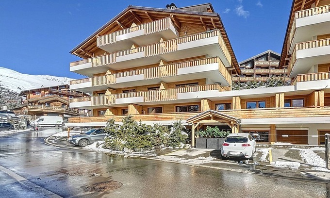 Verbier Apartment | A living room with a sofa bed for 2 people, an open kitchen with a bar, and a Nespresso machine. A s