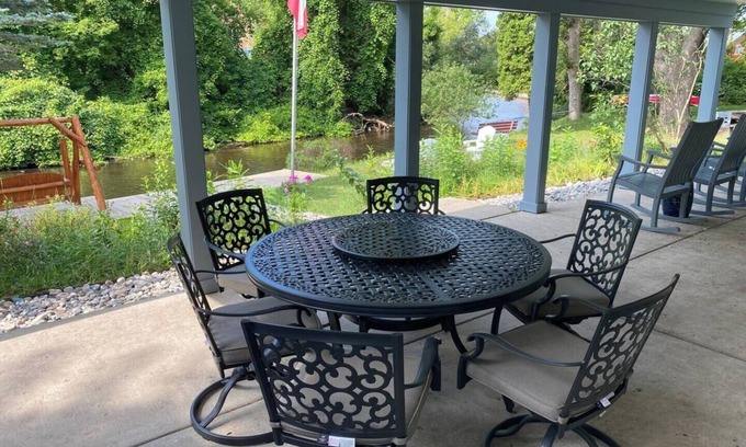Grayling House | Riverfront Escape in Downtown Relax on the Covered Patio with the Family